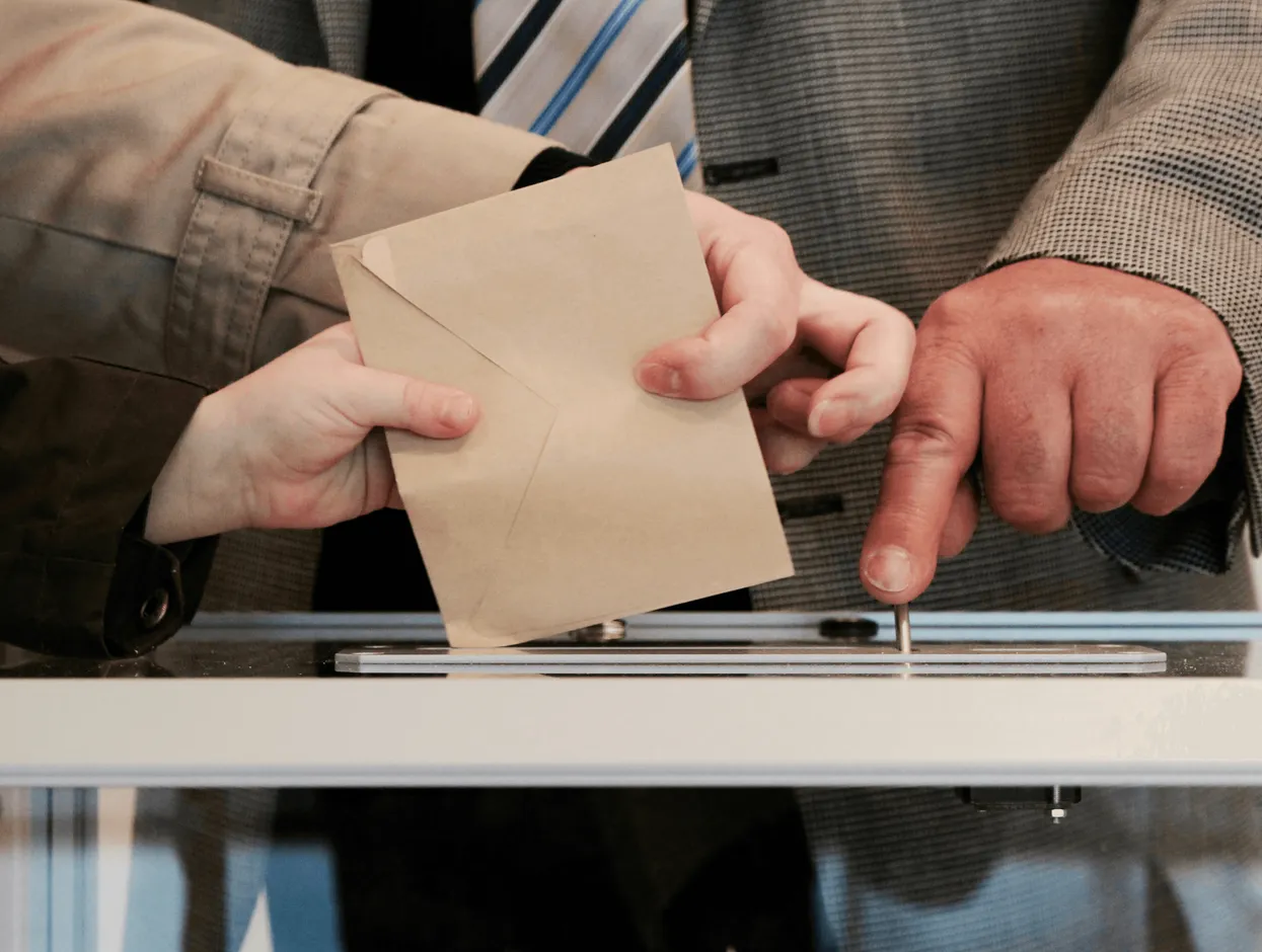 Mano depositando un sobre en una urna